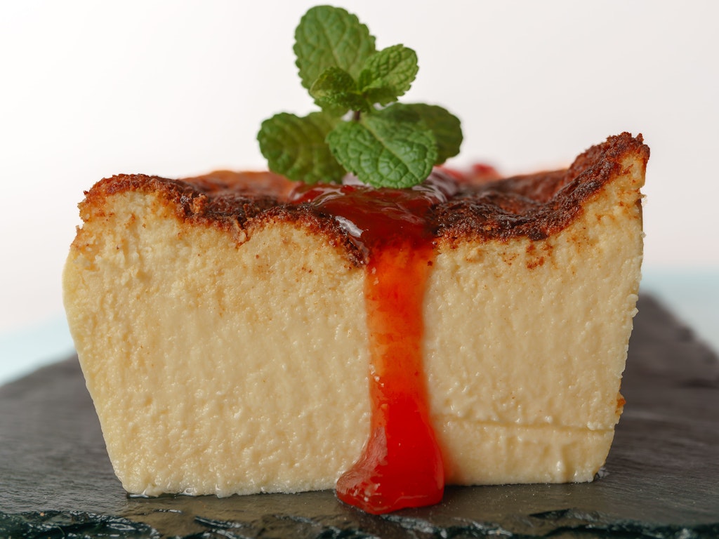 Wer es mag, verfeinert den Käsekuchen mit Minze und etwas Erdbeersauce.