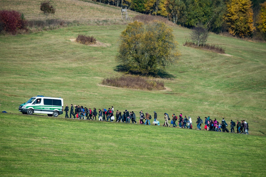 Flüchtlinge gehen in Bayern hinter einem Fahrzeug der Bundespolizei her. Die Länder gehen mit großer Einigkeit in Gespräche mit dem Bund über die strittige Flüchtlingsfinanzierung.