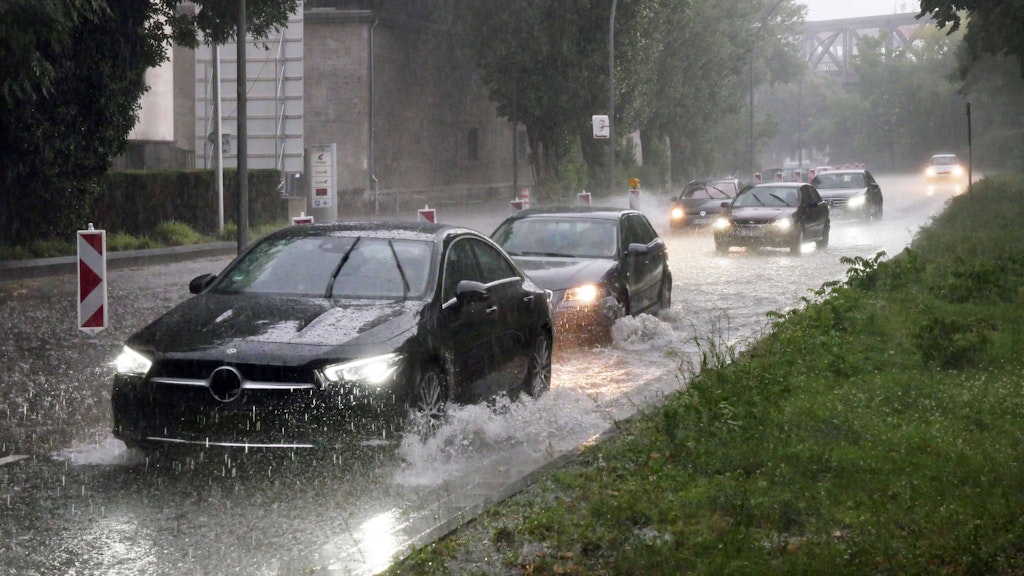 Sommer 2021: Ein heftiges Unwetter mit Starkregen geht nieder, Autos fahren durch riesige Lachen.