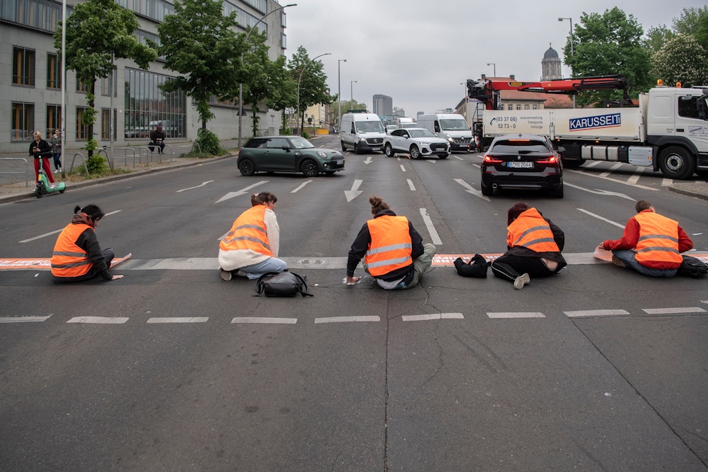 Klimakleber der Letzten Generation sitzen bei einem Protest auf dem Mühlendamm.