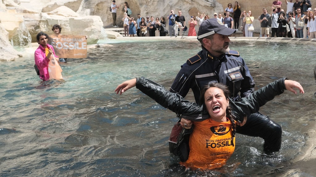 Ein Polizist holt eine Klimaaktivistin aus dem Wasser des Trevi-Brunnens.