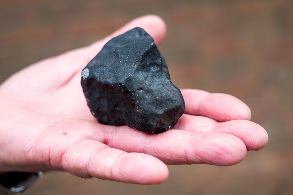 Ein Hausbesitzer hält einen kleinen Meteoriten in der Hand, der in Elmshorn niedergegangen ist. Ein deutlich größeres Stück davon landete im Garten der Familie Sahin.