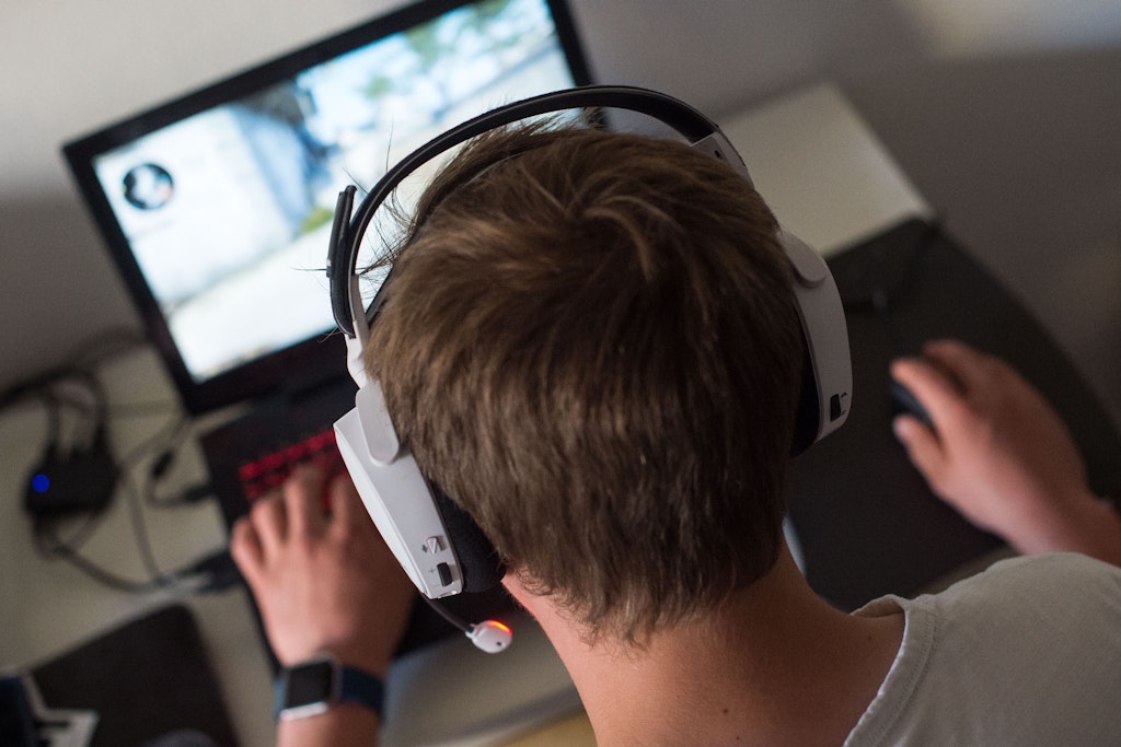 Ein Jugendlicher sitzt mit einem Headset vor einem Laptop und spielt ein Online-Computerspiel. (Symbolbild)