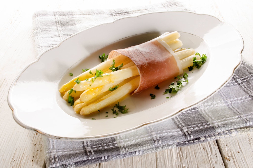 Für frittierten Spargel wird das Gemüse mit Schinken und dann mit Käse umwickelt und danach paniert und frittiert.