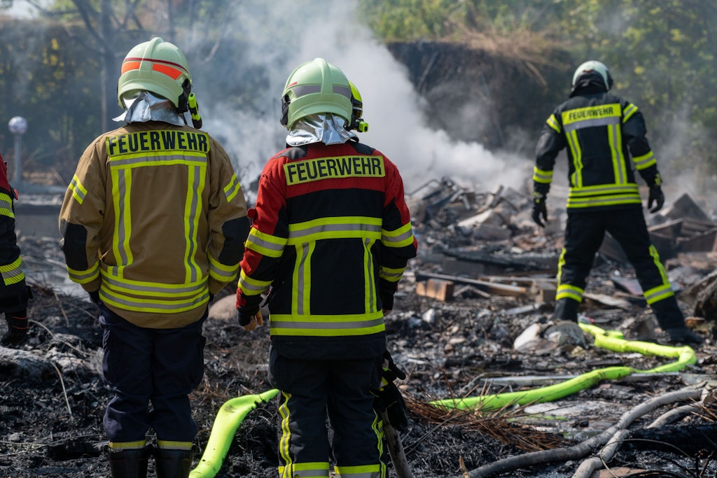 Einsatzkräfte vor dem zerstörten Haus.