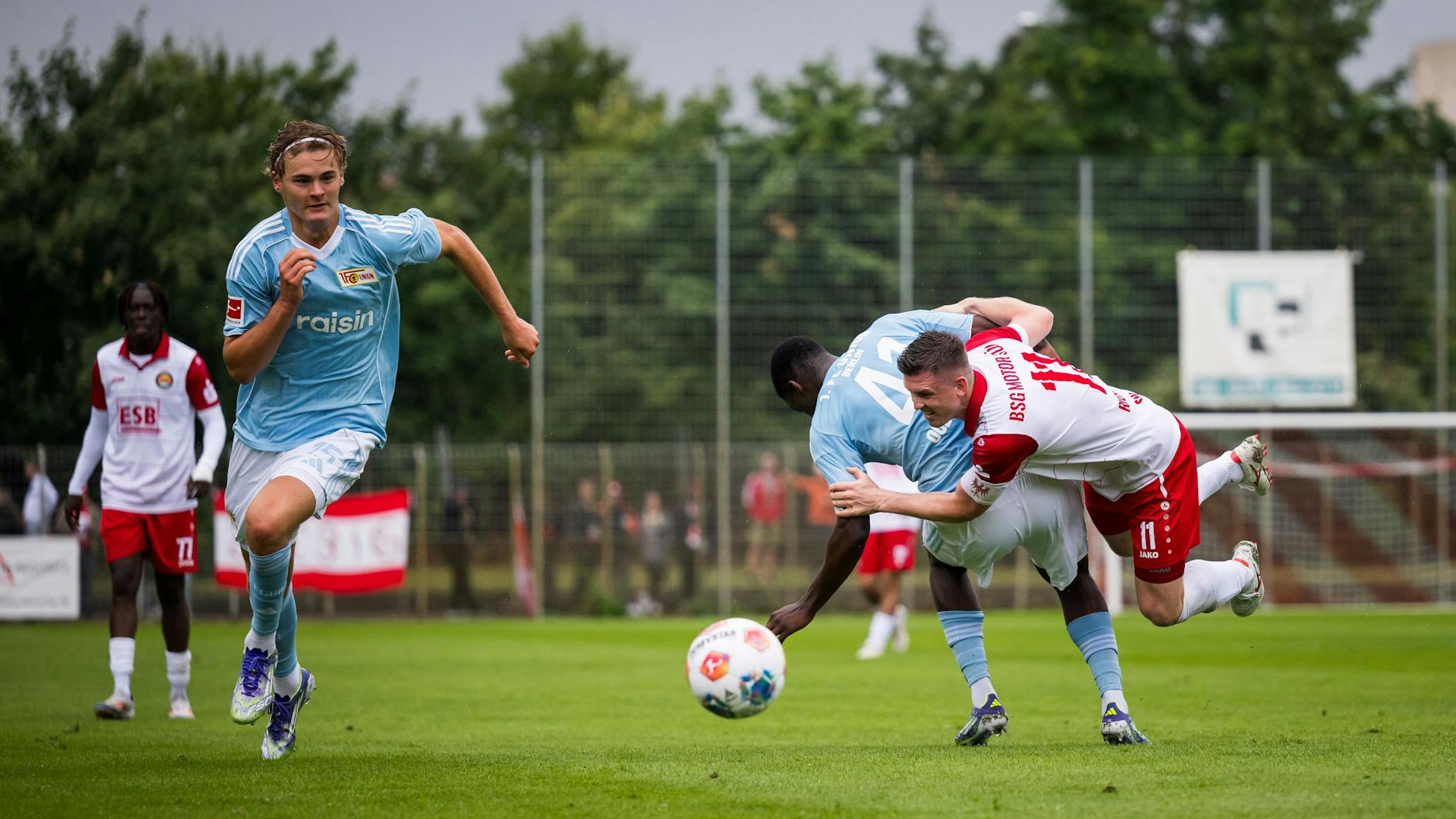 Während Oluwaseun Ogbemudia für den 1. FC Union vollen Einsatz im Zweikampf zeigt, sprintet Tom Rothe dem Ball hinterher.