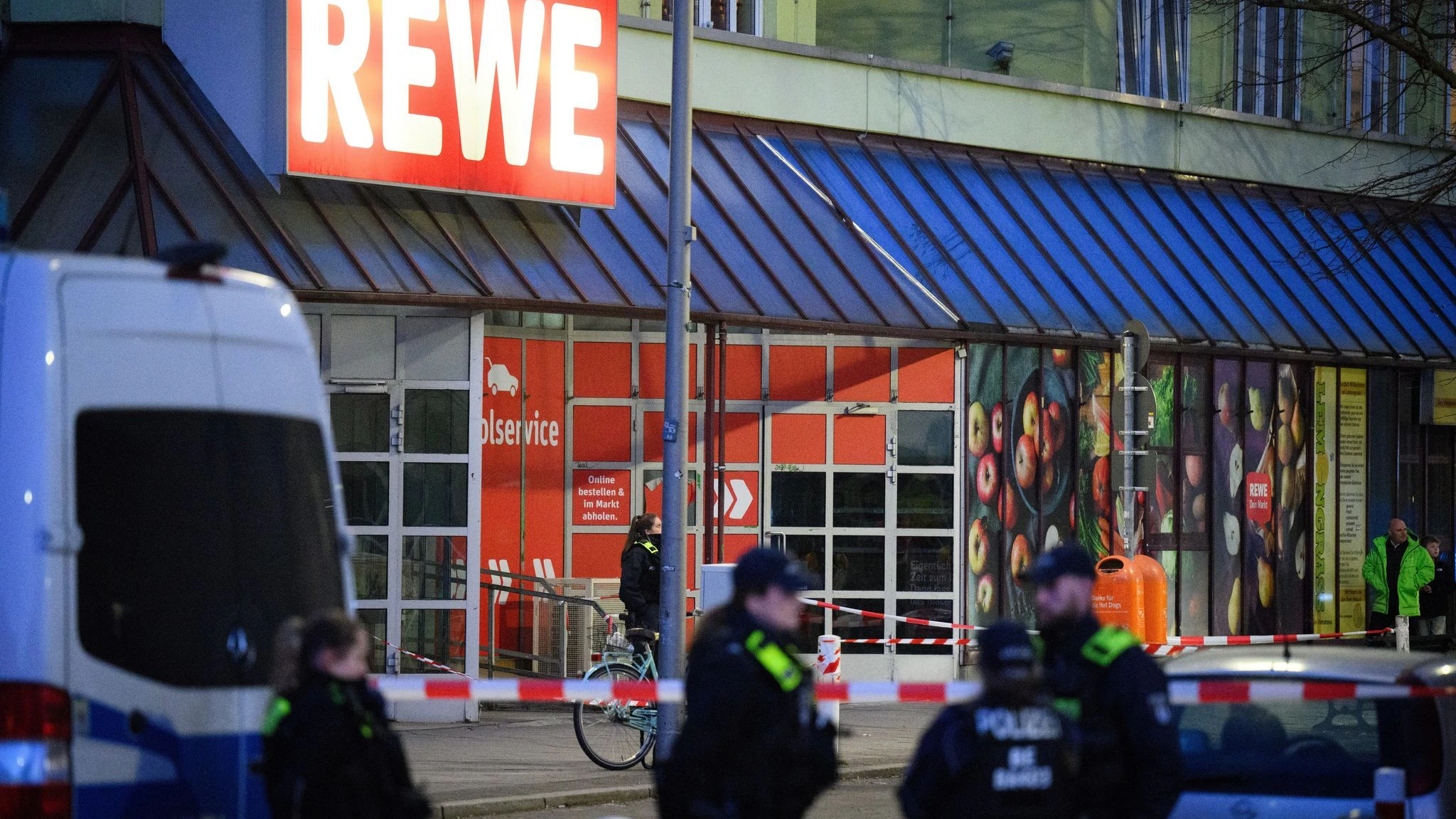 Polizisten stehen an einem abgesperrten Bereich vor einem Supermarkt in Berlin-Charlottenburg. Hier ereignete sich am Silvestertag der brutale Angriff mit einem Messer.