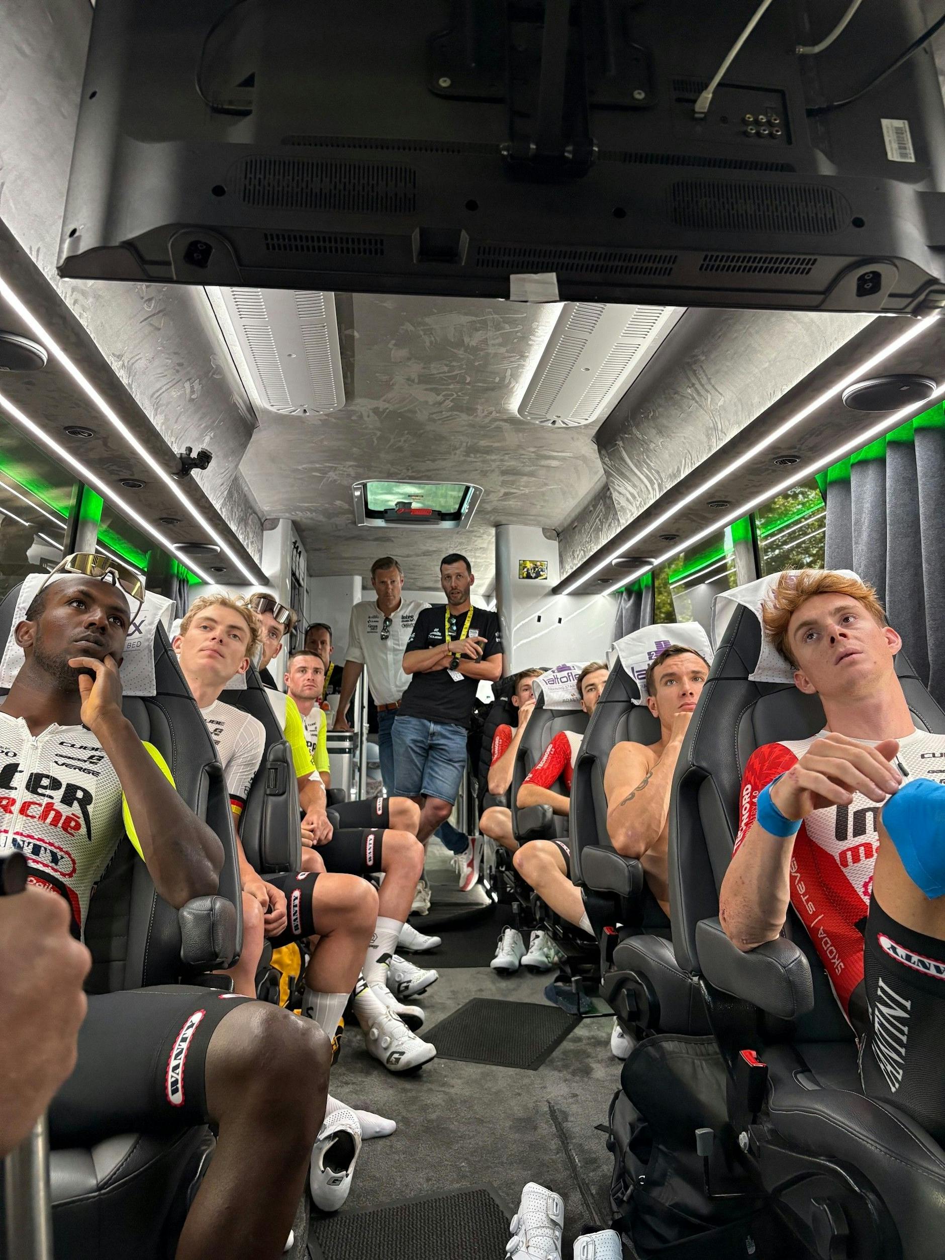 Die Fahrer des Teams Intermarché-Wanty verfolgen auf dem Bildschirm im Bus die Taktik-Anweisungen für das Rennen.