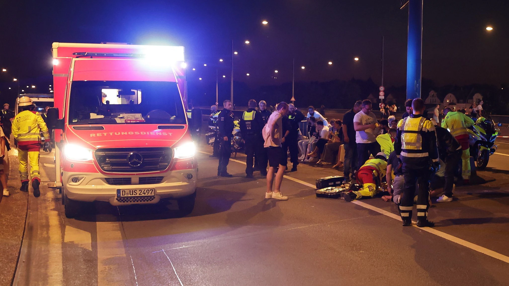 Rettungskräfte kümmern sich um einen Verletzten auf einer Brücke. Auf der Rheinkirmes war ein Feuerwerkskörper unkontrolliert explodiert.