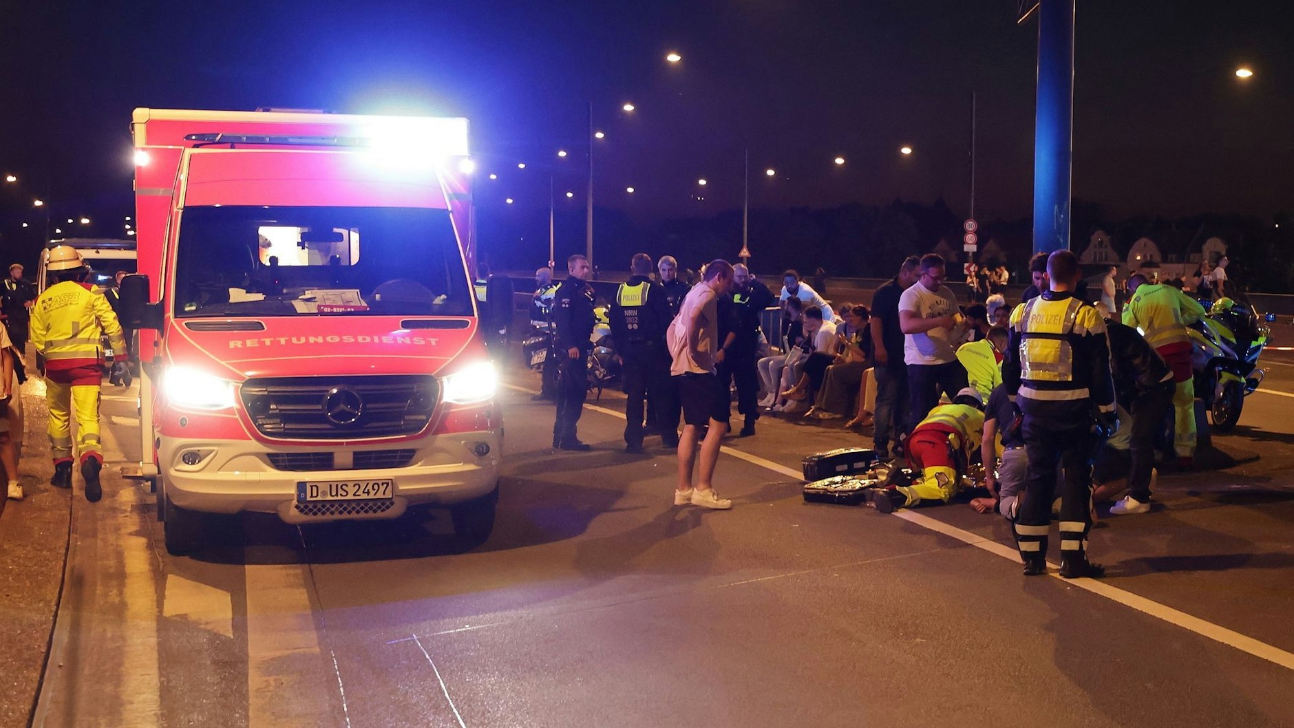 Rettungskräfte kümmern sich um einen Verletzten auf einer Brücke. Auf der Rheinkirmes war ein Feuerwerkskörper unkontrolliert explodiert.