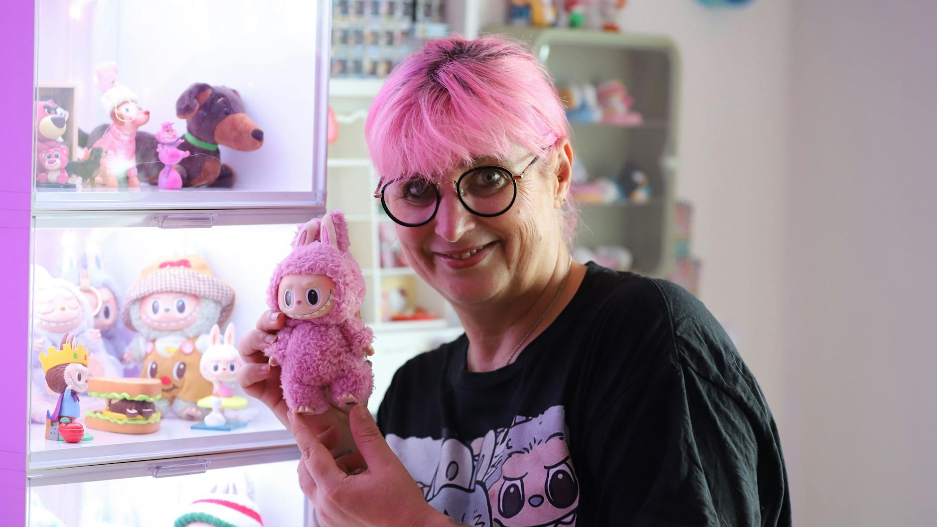 Influencerin Jean steht in ihrer Wohnung und hält einen Labubu in der Hand.