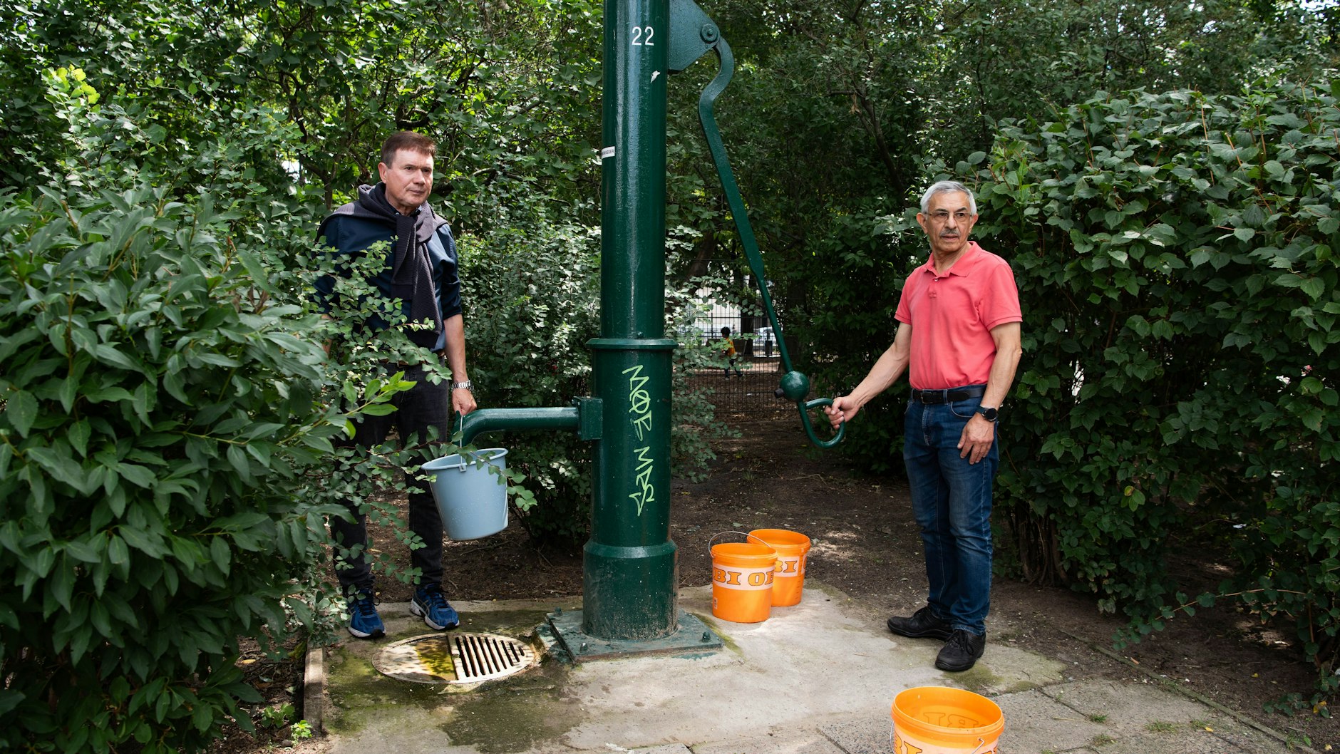 Auf der Fischerinsel in Berlin-Mitte: Aus der alten dunkelgrünen Wasserpumpe werden acht Eimer à 10 Liter abgepumpt, um die Wassertemperatur zu messen.
