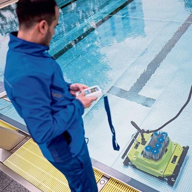Becken putzen muss man auch wenn wenig Gäste kommen. Ein Mitarbeiter arbeitet in Berlin im Kombibad Gropiusstadt mit einem Saugroboter.