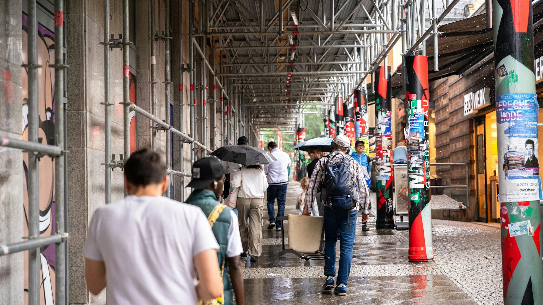 Passanten gehen an der Frankfurter Allee unter den Baustellengerüsten entlang.