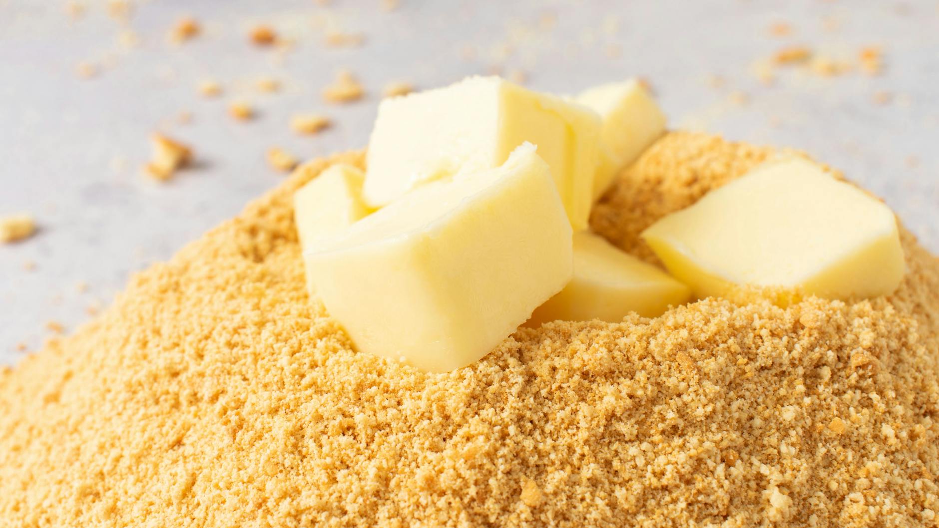 Aus Keks-Krümeln, Butter und Zucker wird der Boden für den Käsekuchen.