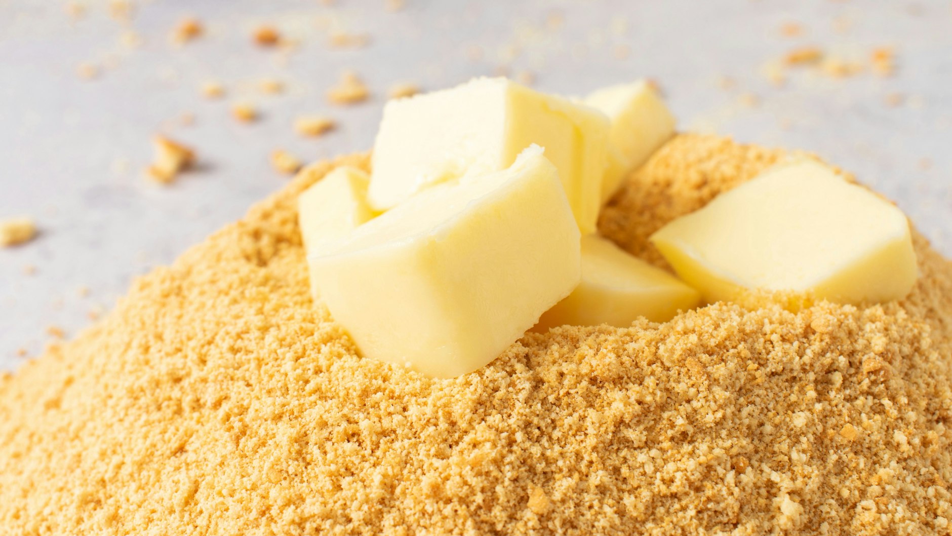 Aus Keks-Krümeln, Butter und Zucker wird der Boden für den Käsekuchen.