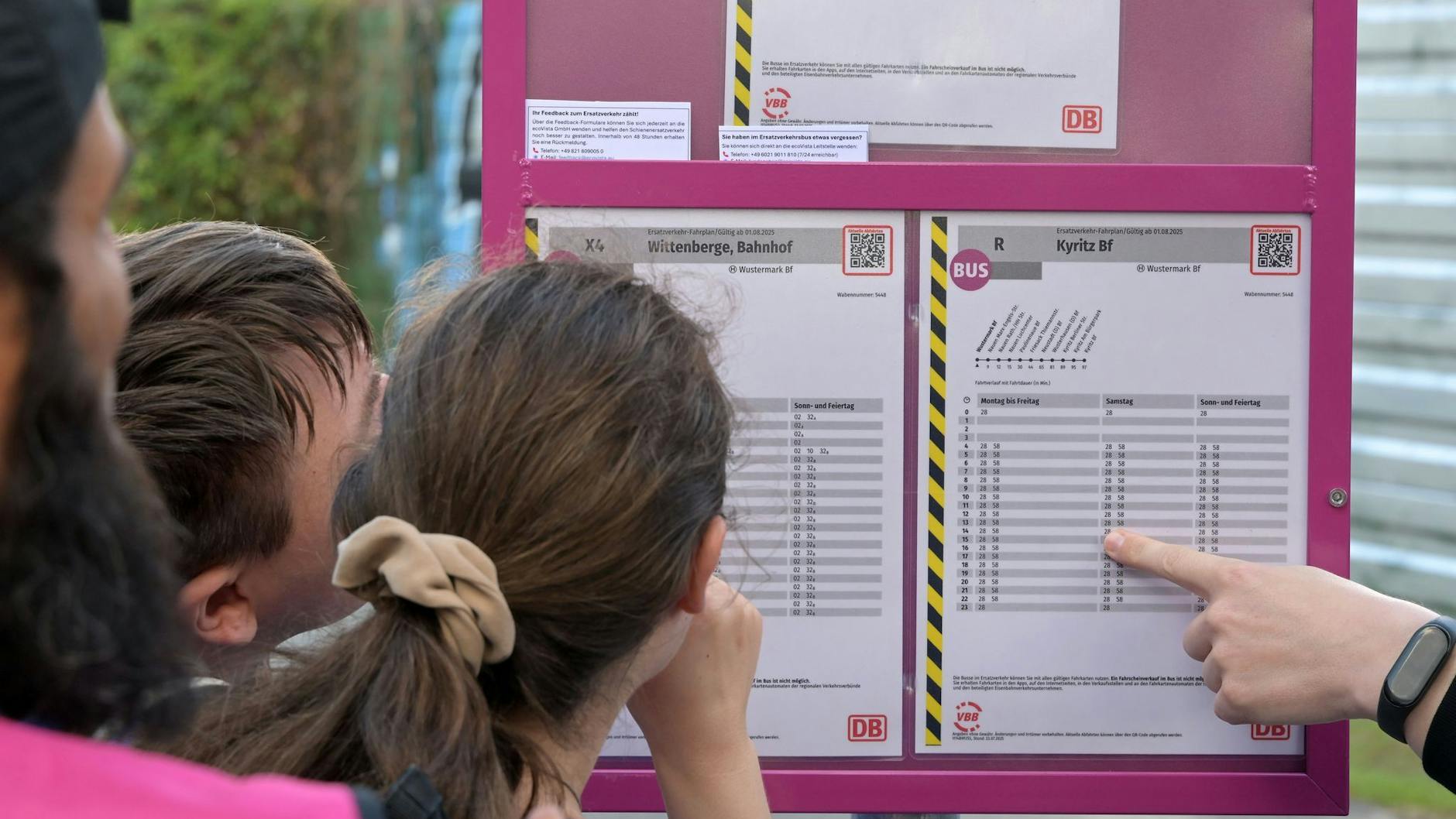 Fahrgäste schauen an einem Bahnhof auf einen Fahrplan für Ersatzbusse, 170 Busse sind im Einsatz.