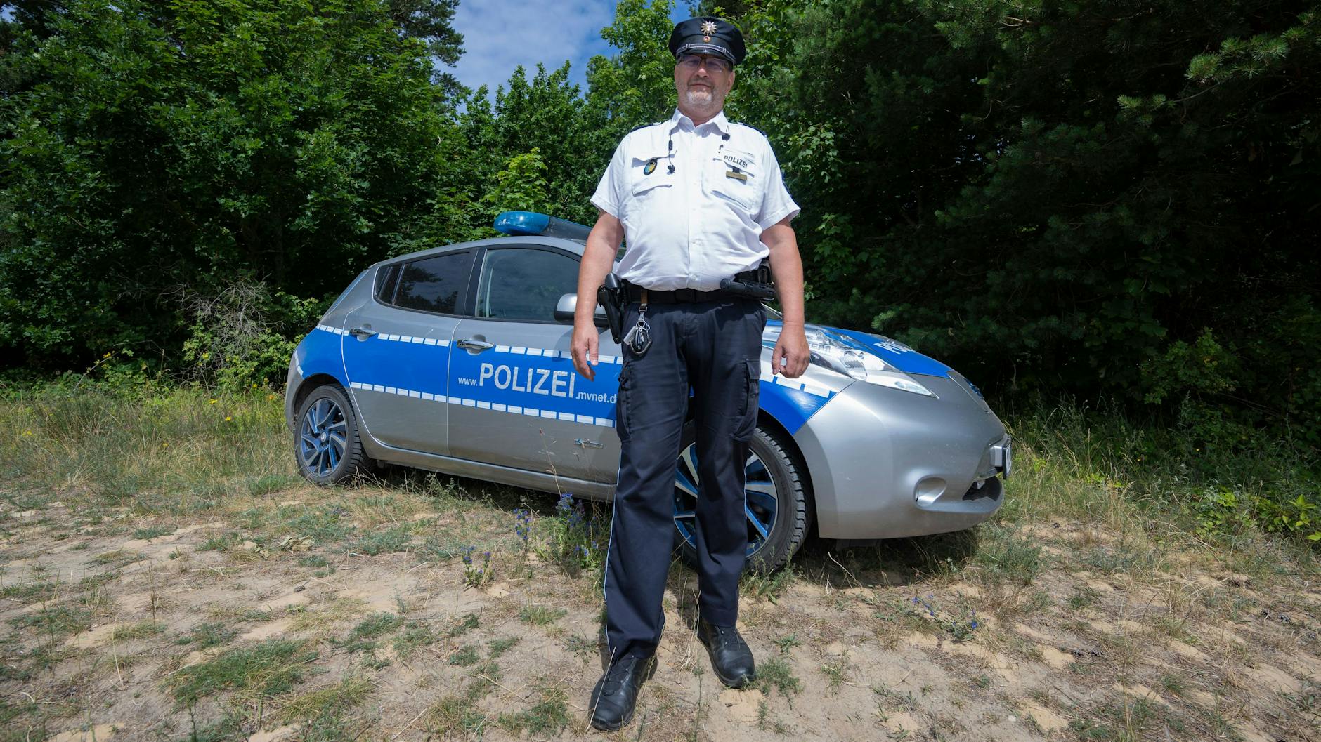 Hiddensees einziger Polizist Thomas Moritz vor seinem E-Streifenwagen