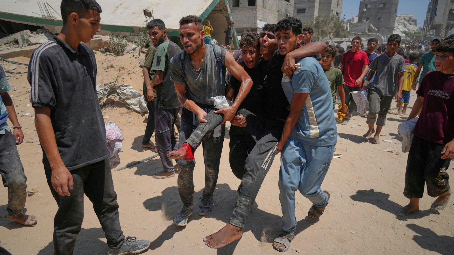 Palästinenser tragen einen Mann, der verletzt wurde, als er humanitäre Hilfsgüter einsammeln wollte, die per Fallschirm abgeworfen wurden.