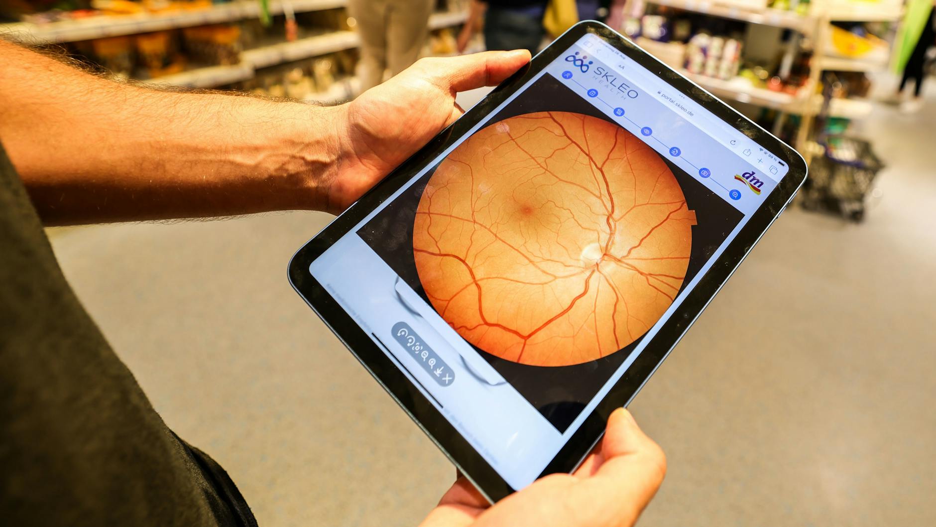 Auf einem Tablet wird nach der Untersuchung die fotografierte Netzhaut im Auge des Kunden gezeigt.