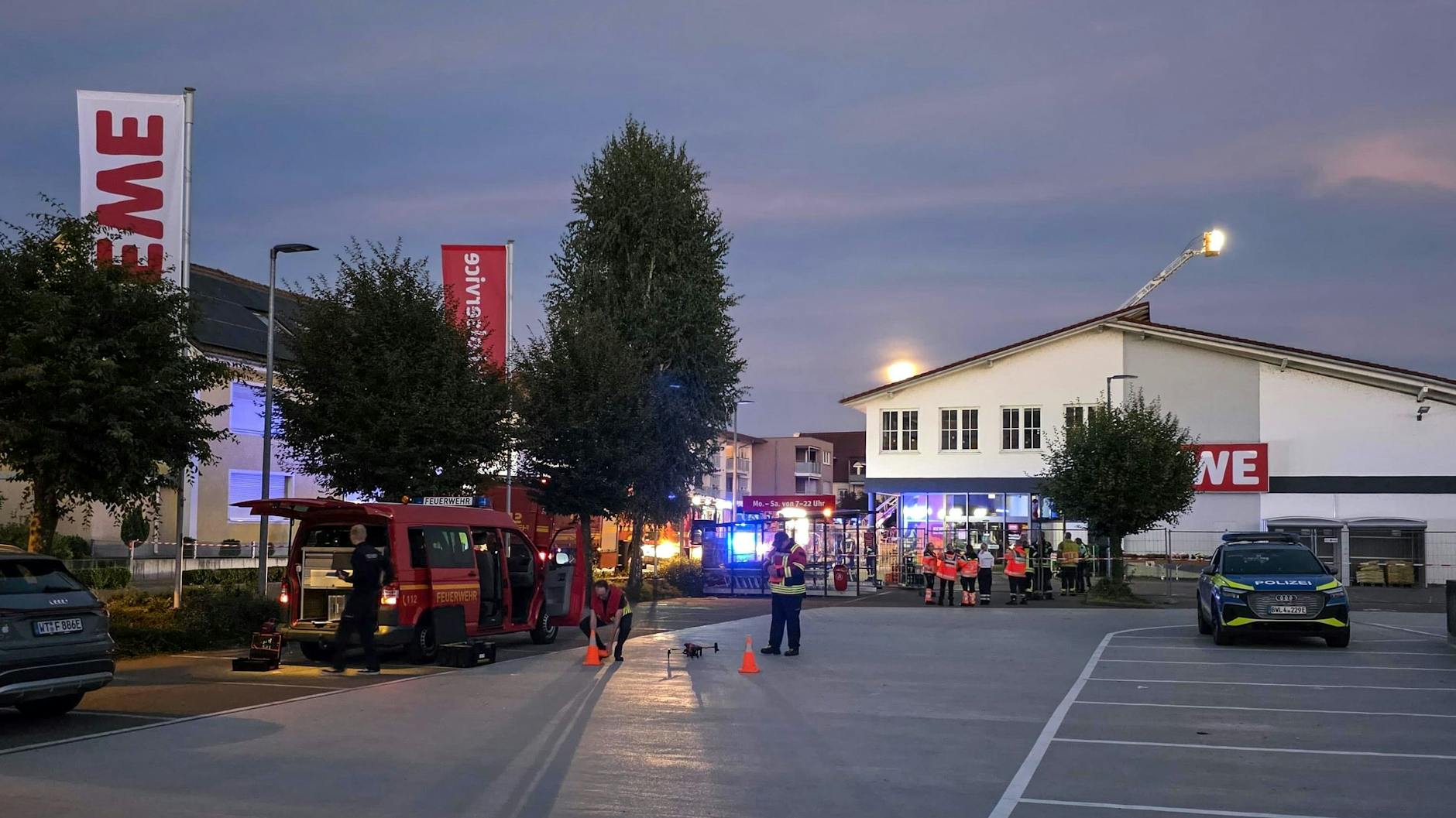 Einsatzkräfte stehen vor dem Eingang zum Supermarkt.