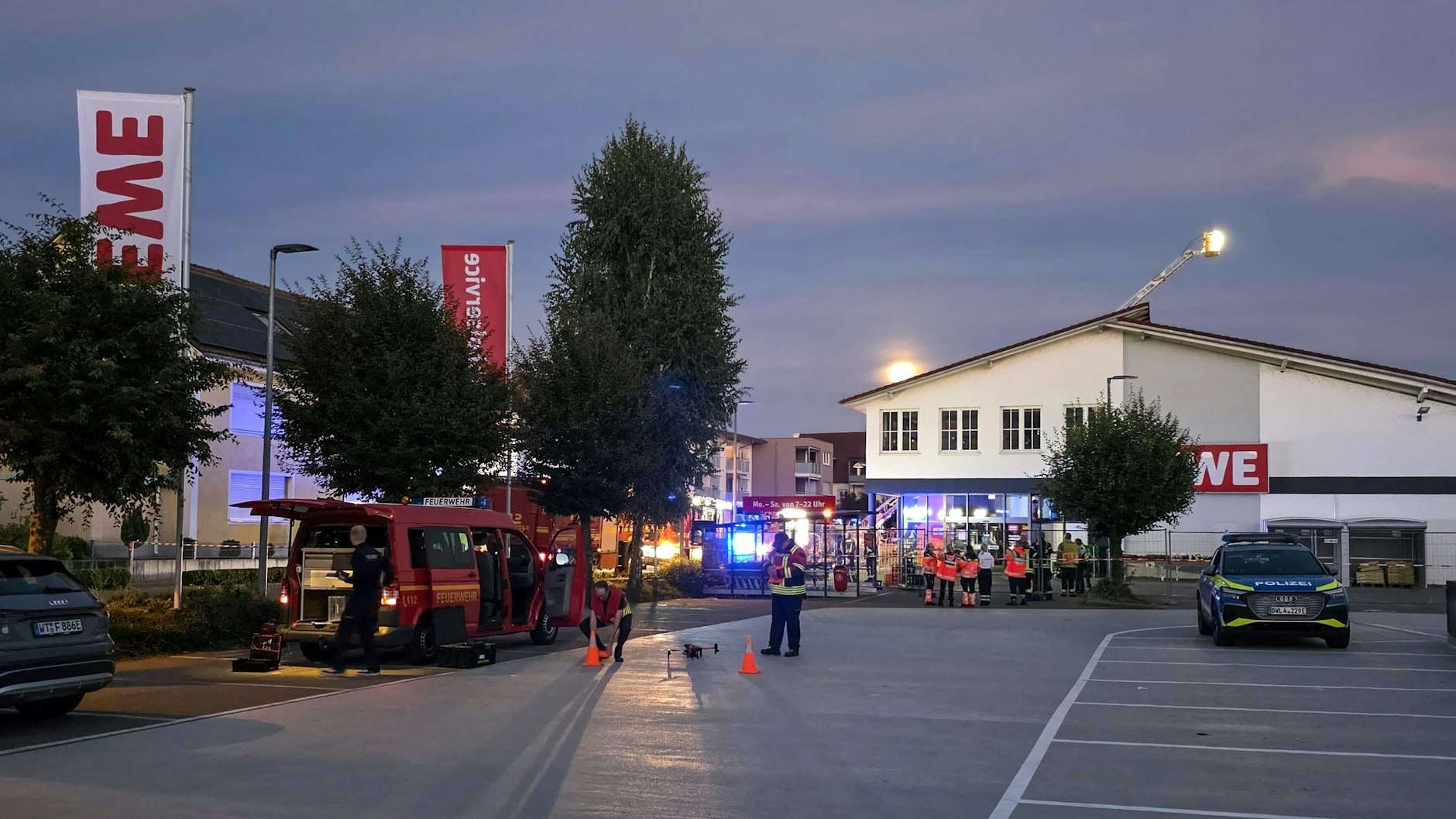 Einsatzkräfte stehen vor dem Eingang zum Supermarkt.