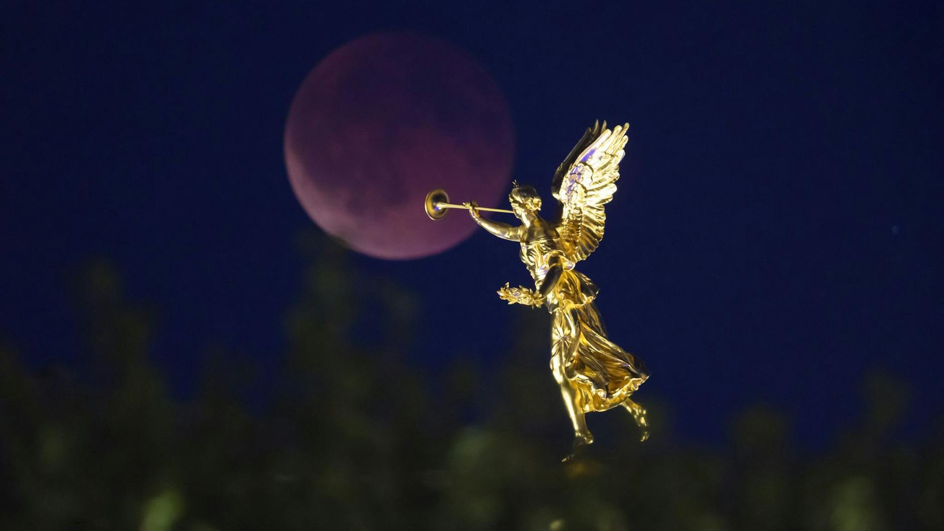 Der Mond geht am Abend zu einer totalen Mondfinsternis hinter dem Engel auf der Kunstakademie in Dresdenauf.
