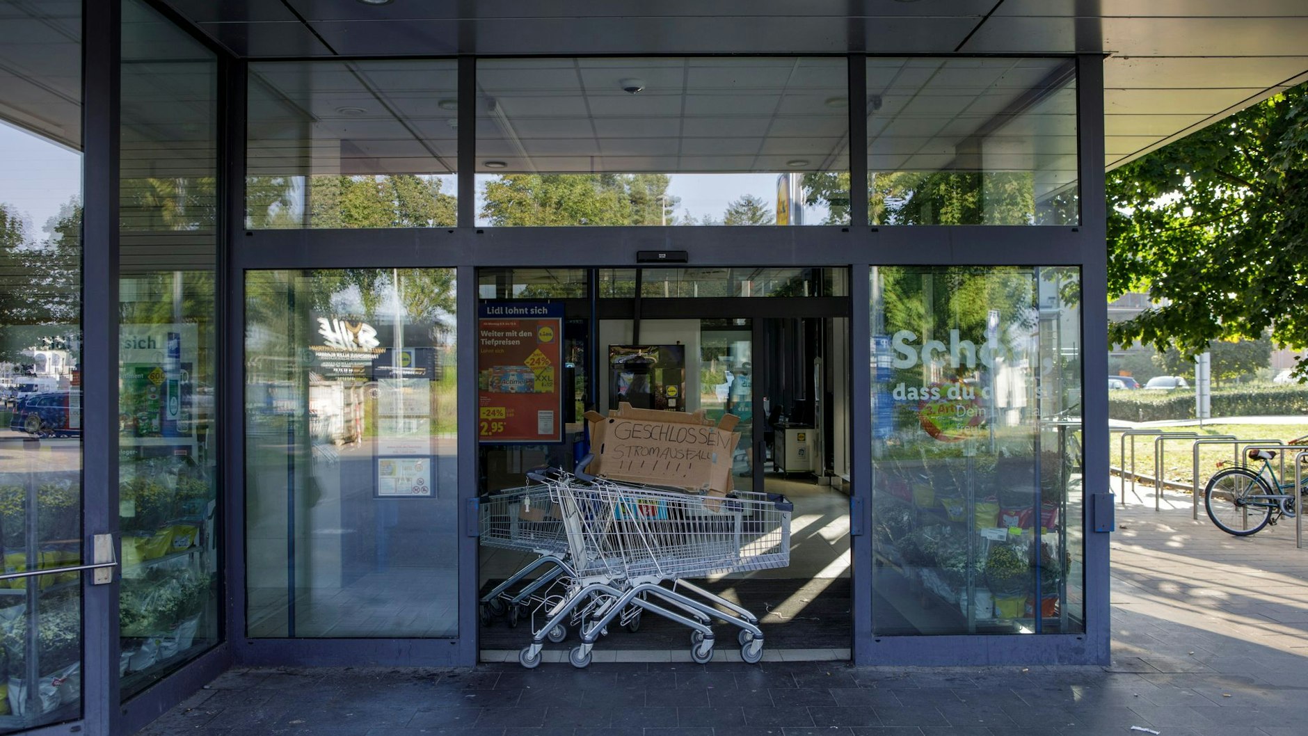 Im Eingang eines Supermarkts steht ein Einkaufswagen mit einer Pappe und der Aufschrift „Geschlossen, Stromausfall!“.