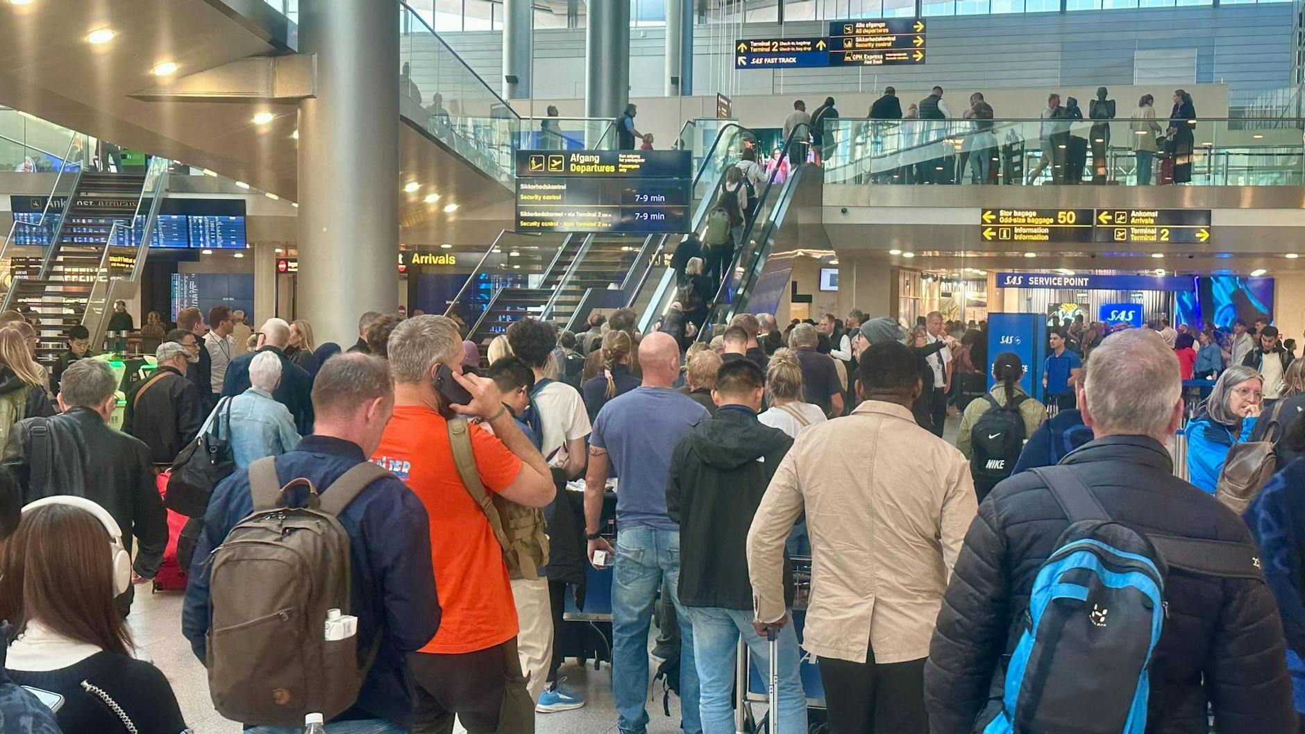 Reisende warten am Flughafen in Kopenhagen an einem Service-Schalter. Die Sichtung mehrerer großer Drohnen hat für eine stundenlange Sperrung des Luftverkehrs gesorgt.
